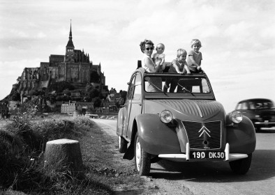 Une 2 CV devant le Mont Saint-Michel en 1960, une femme et ses trois enfants sortent par le toit ouvrant. Photo de Georges Guyot. Utilisation ιditoriale uniquement, nous contacter pour toute autre utilisation