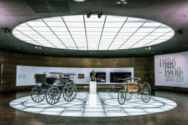 Mercedes-Benz Museum, Stuttgart. Benz Patent-Motorwagen (rechts) und Daimler Motorkutsche (links) im Raum Mythos 1: Pioniere – Die Erfindung des Automobils, 1886 bis 1900. In der Mitte die Daimler „Standuhr“ – der erste kleine, schnelllaufende Verbrennungsmotor. (Fotosignatur der Archive von Mercedes-Benz Classic: D587470)
Mercedes-Benz Museum, Stuttgart. Benz Patent Motor Car (right) and Daimler Motor Carriage (left) in room Legend 1: Pioneers – The Invention of the Automobile, 1886 to 1900. In the centre is the Daimler “grandfather clock” – the first small, high-speed combustion engine. (Photo reference number in the Mercedes-Benz Classic Archives: D587470)
